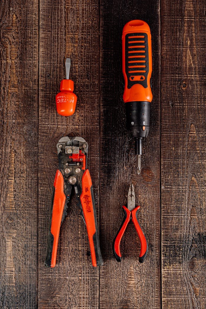 Flat lay view of various red tools on a wooden surface, perfect for DIY and workshop themes.